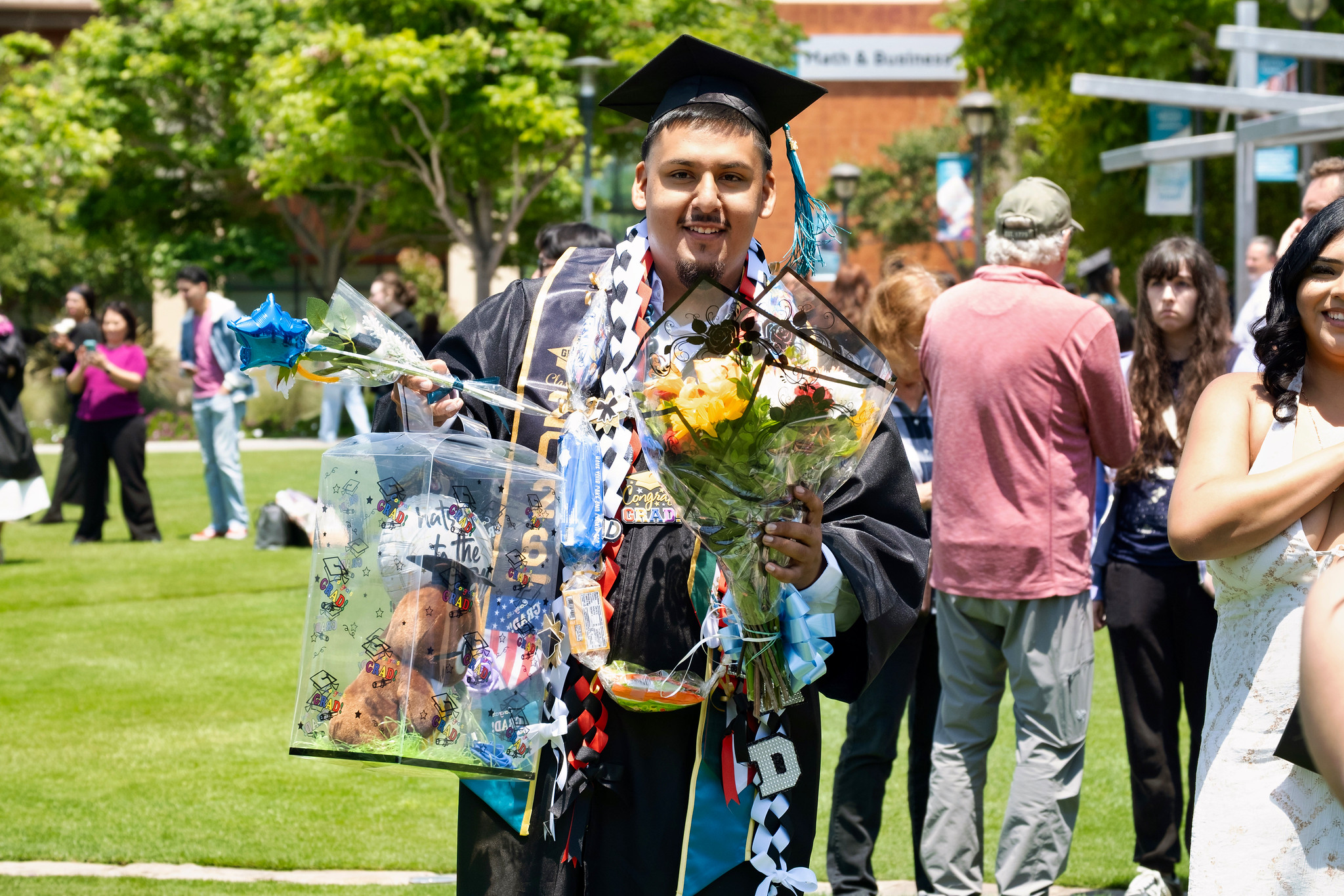 A graduate holding flowers and his degree.