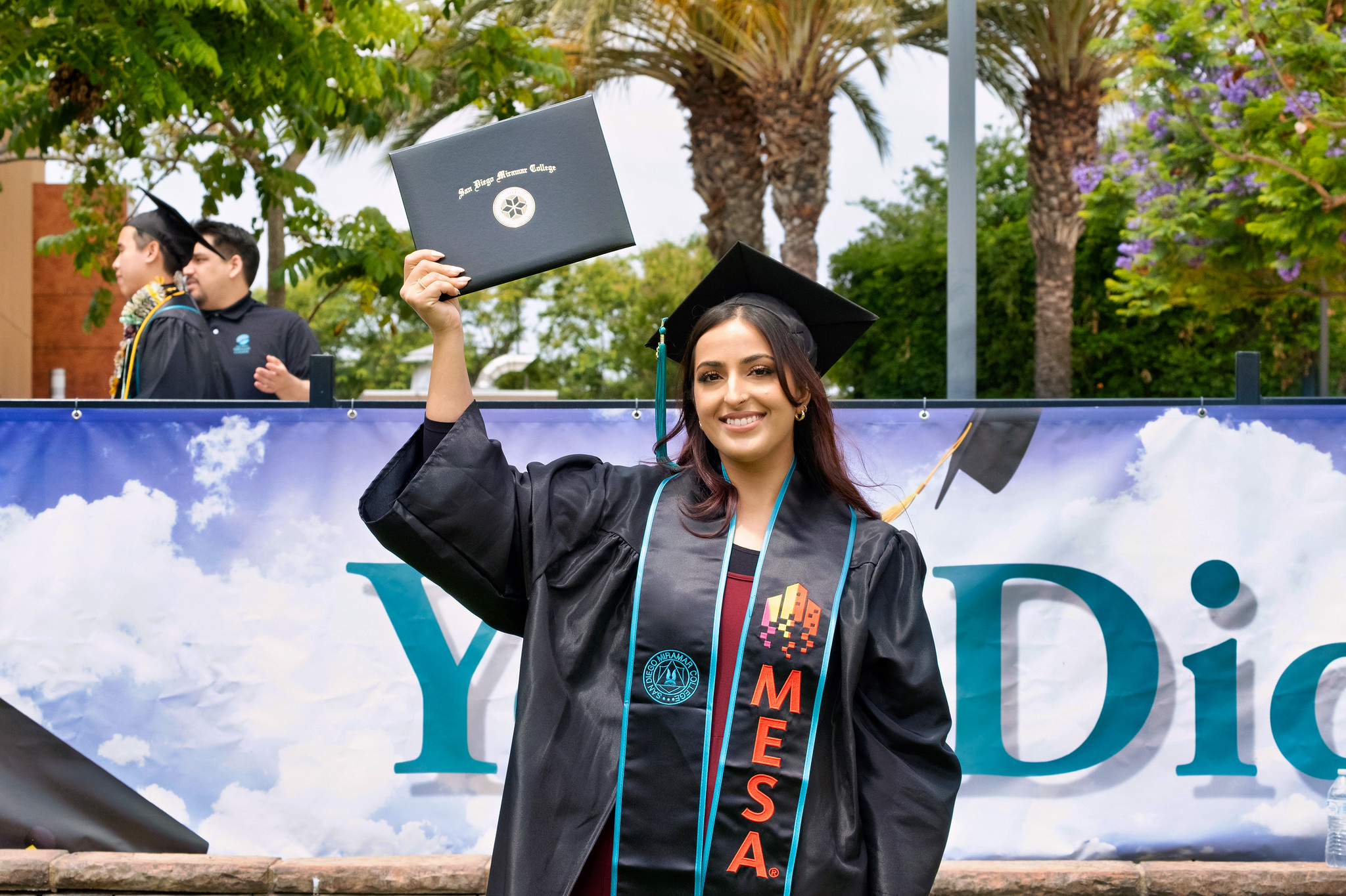 A student holds up their degree.