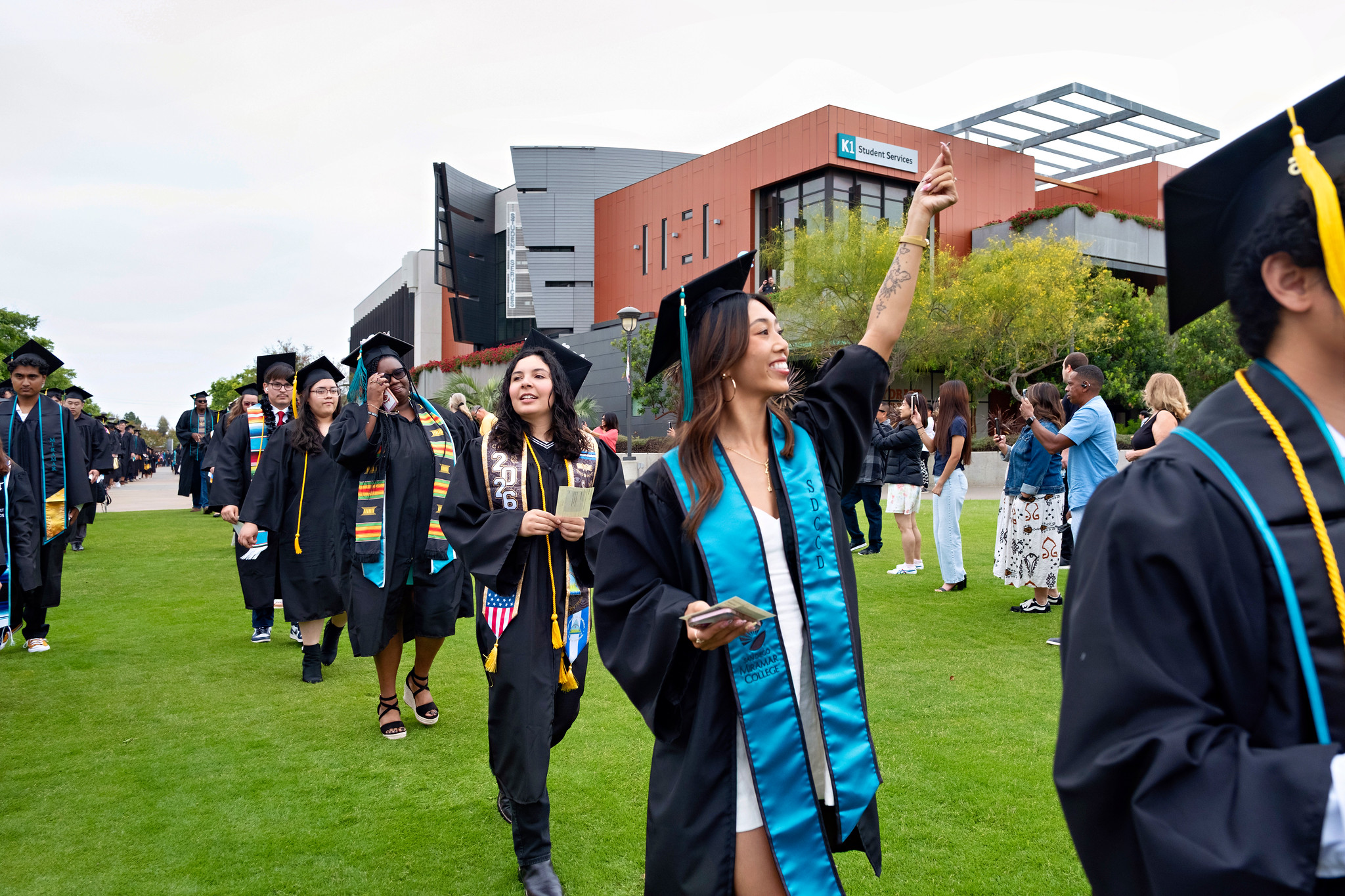 A graduate waving as she heads to her seat at the start of the ceremony.&nbsp;