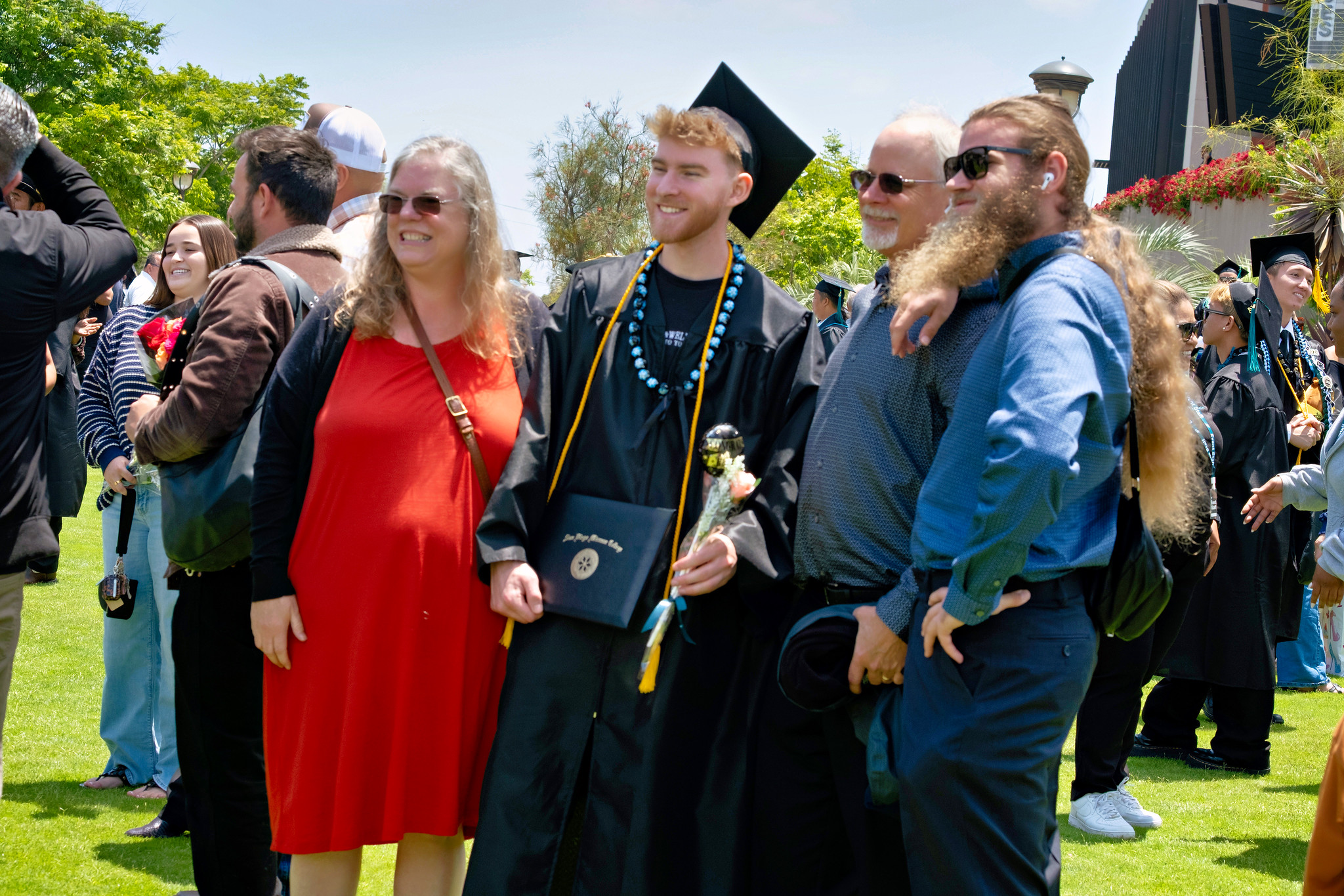 A graduates takes a photo with three family members.&nbsp;