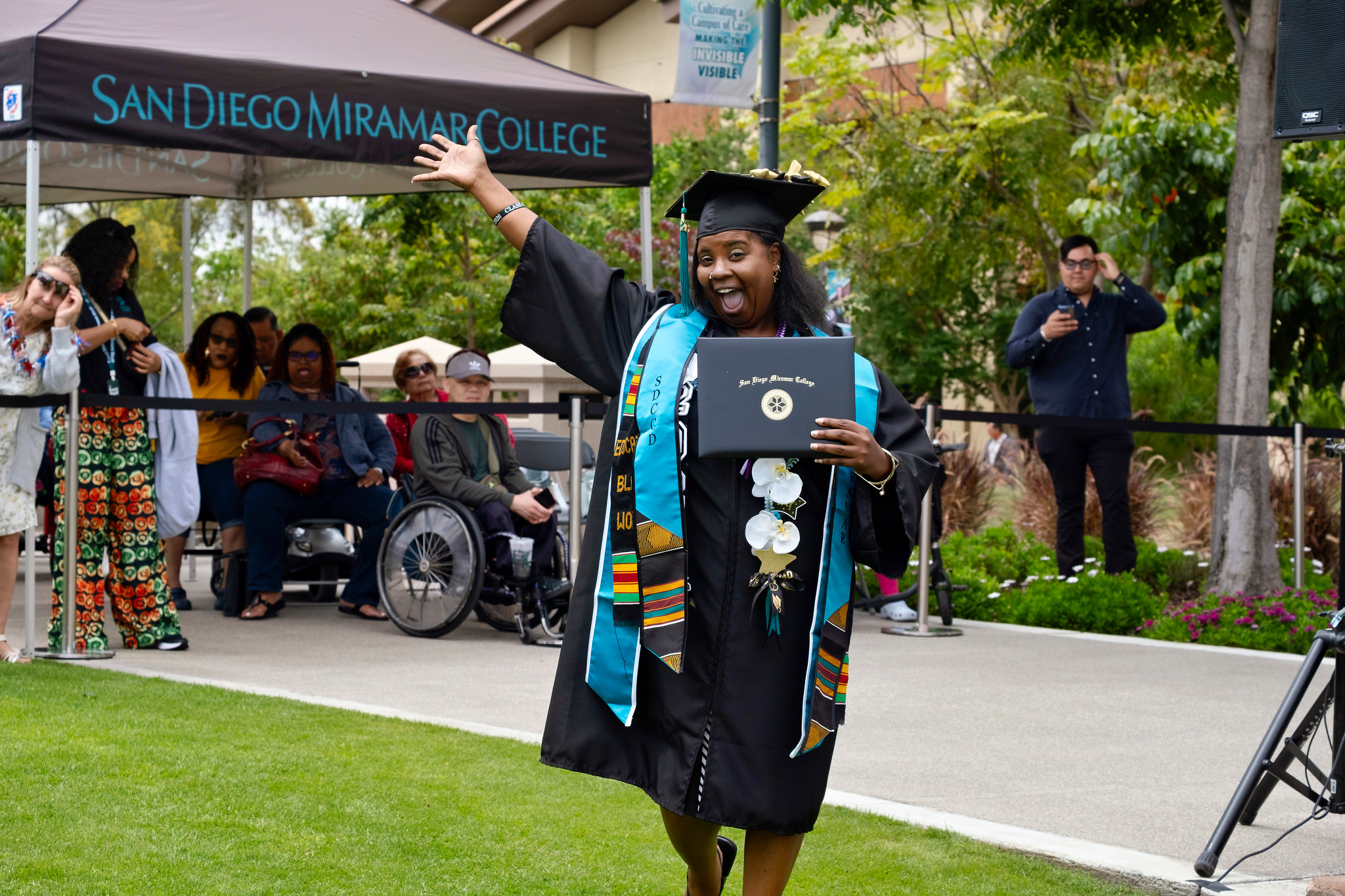 A student holds up their degree.