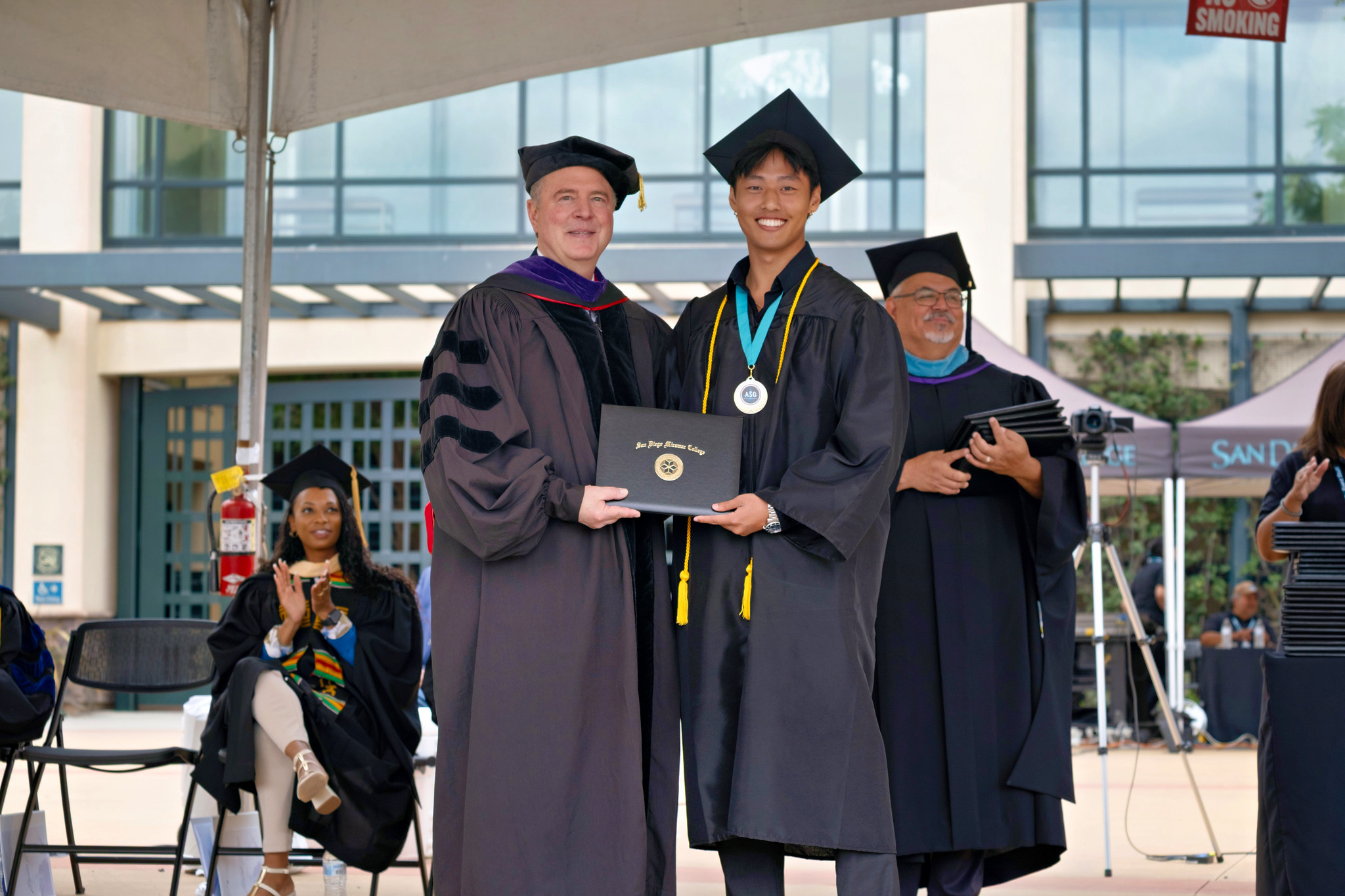 U.S. Senator Adam Schiff gives the student Commencement Speaker his degree.&nbsp;