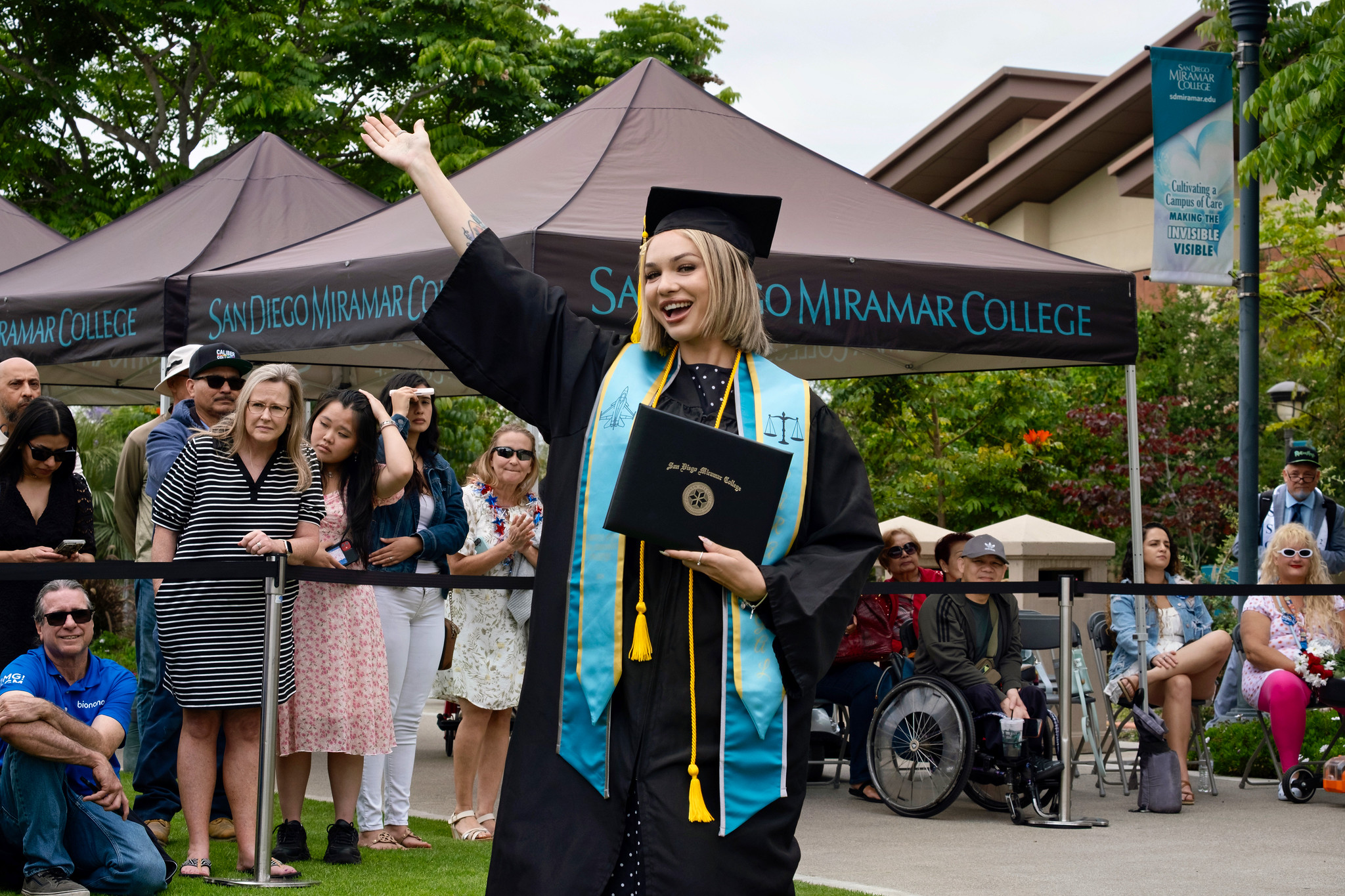 A student holds up their degree.