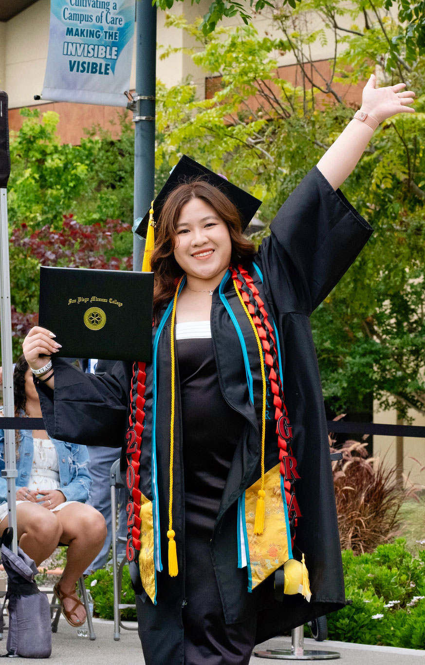 A student holds up their degree.