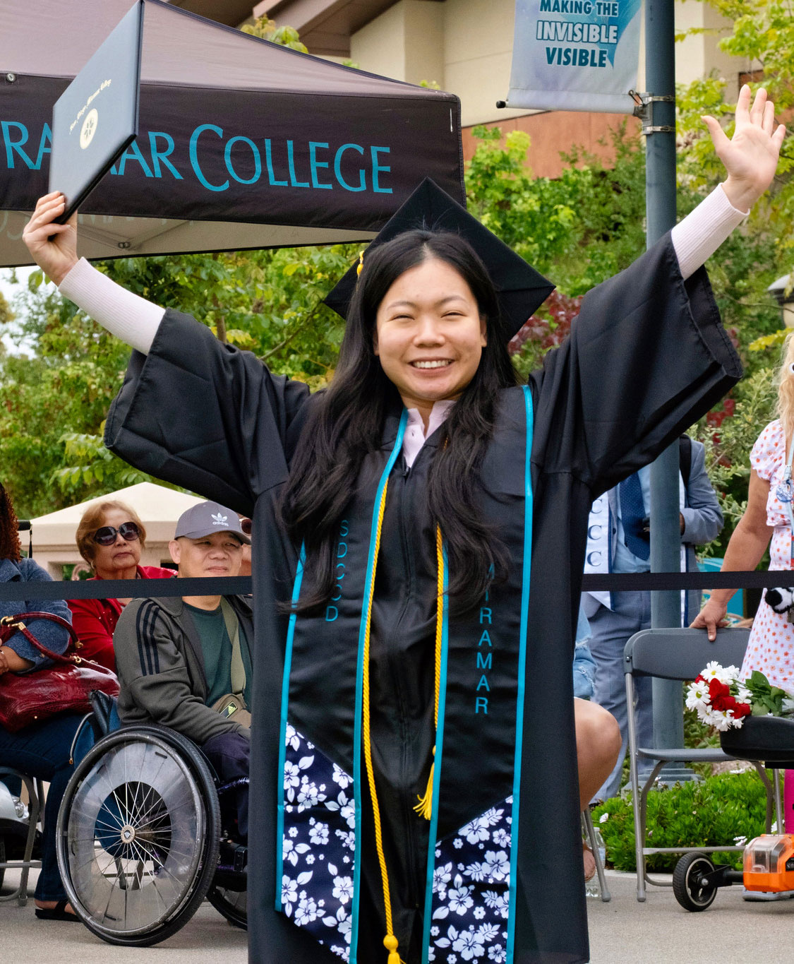 A student holds up their degree.