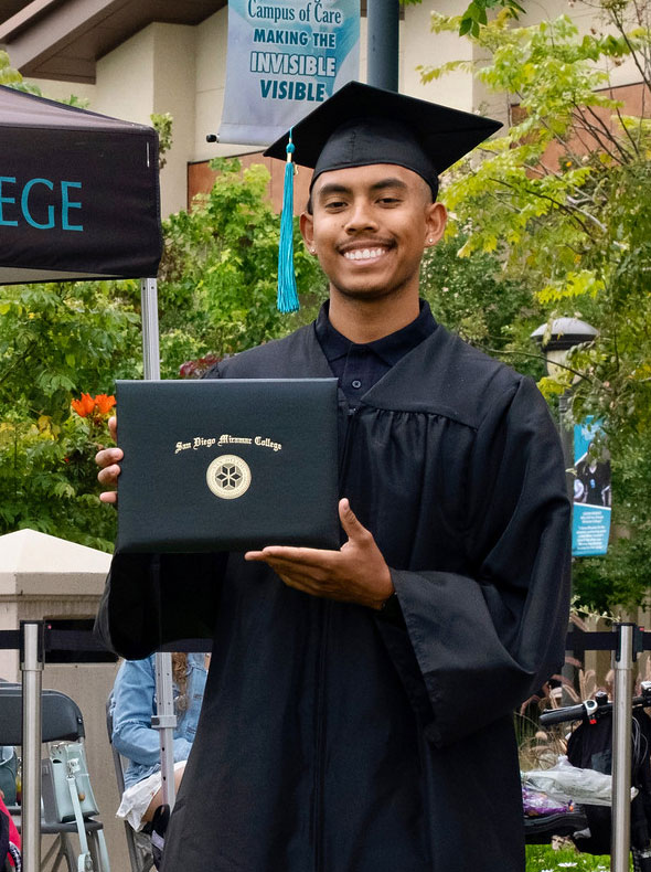A student holds up their degree.