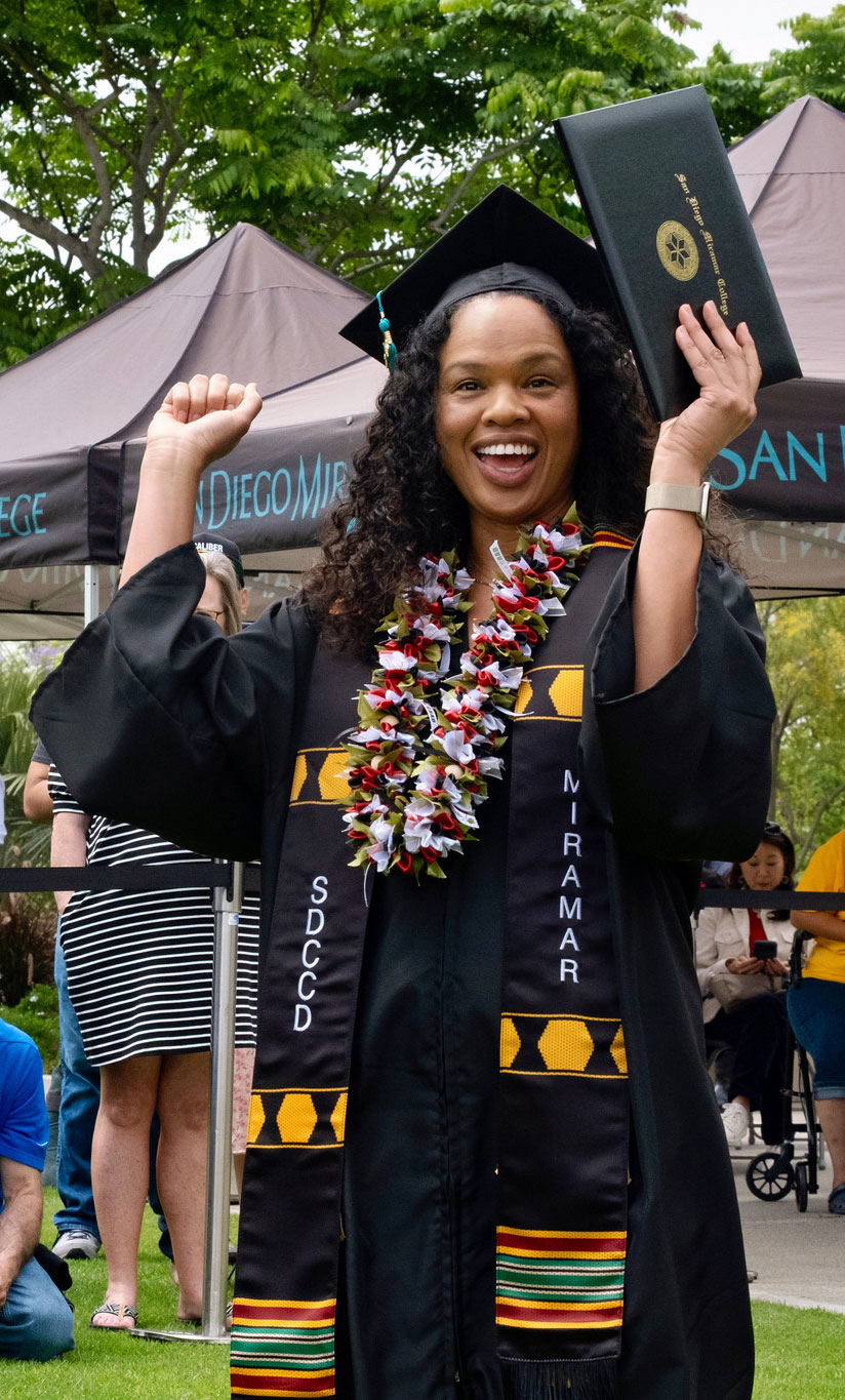 A student holds up their degree.
