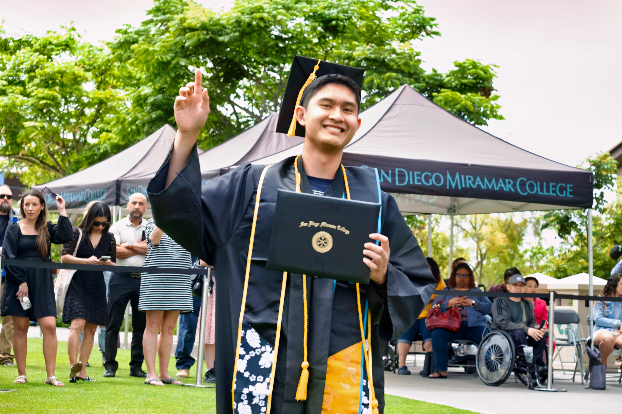 A student holds up their degree.