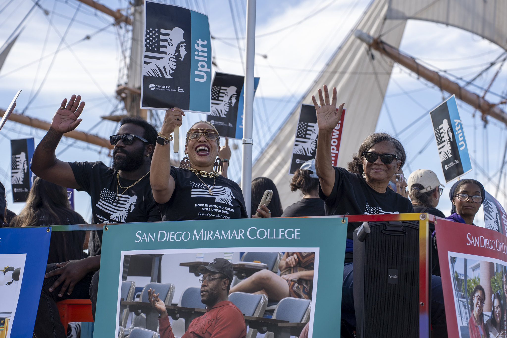 A group of people wave from the SDCCD float at the MLK parade.