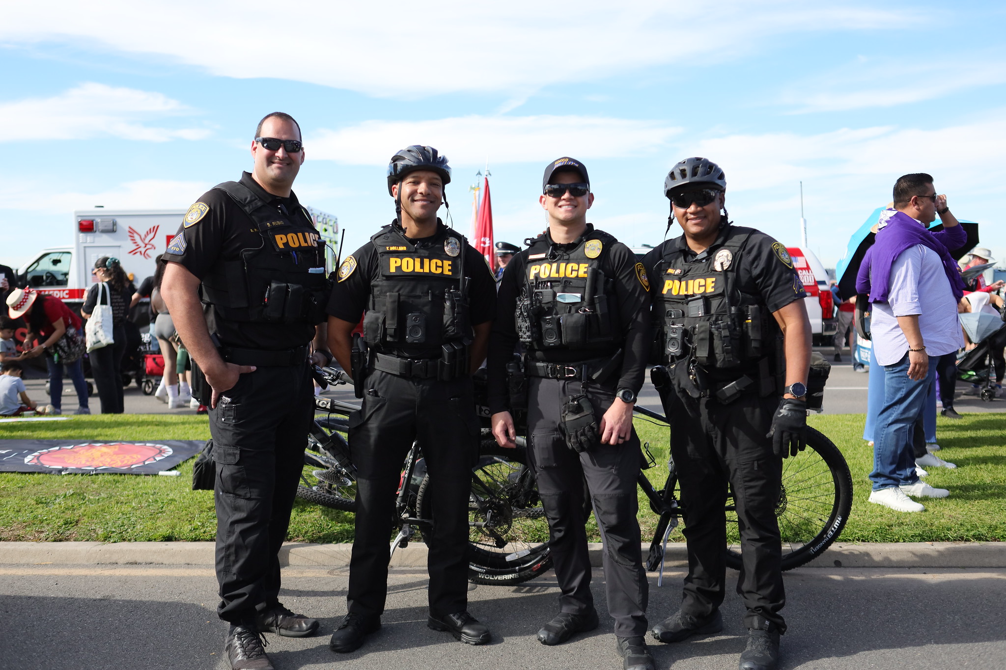 Four college police officers next to the bicycles they rode in the parade.