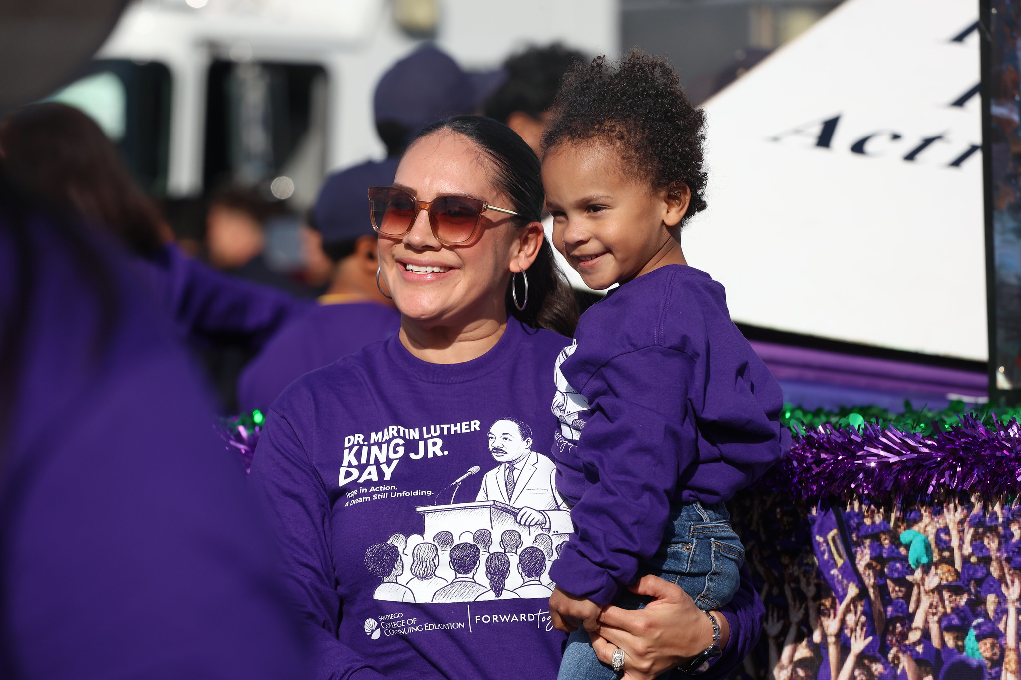 A lady holding a toddler at the parade.