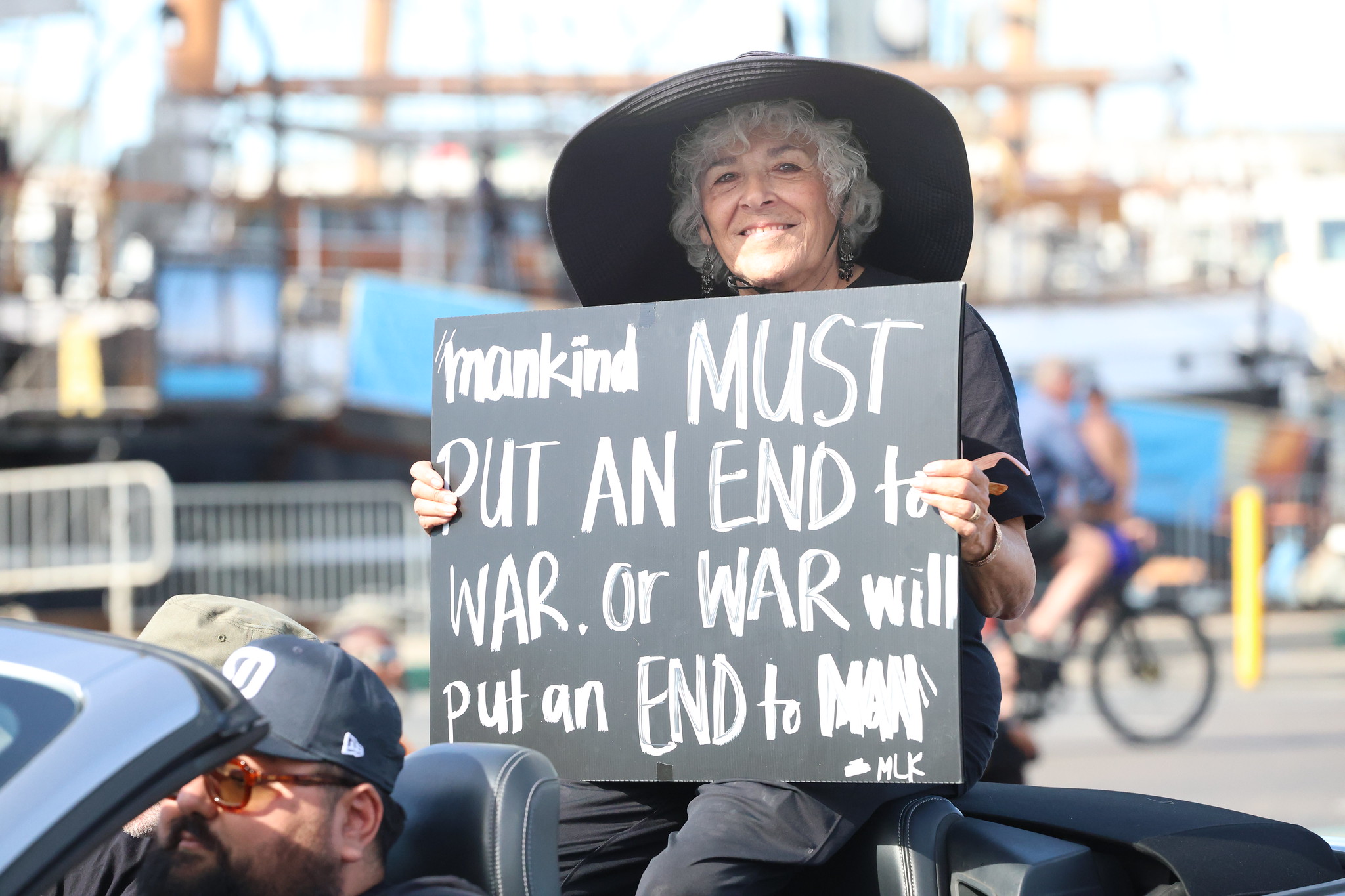 Trustee Maria Nieto Senour holds a sign while riding in a convertible car in the parade.