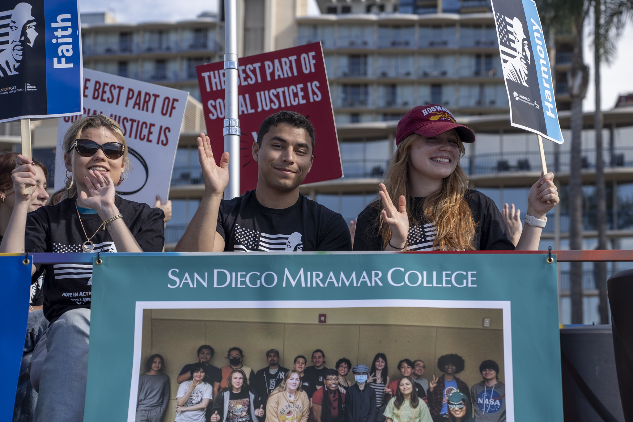 Three people wave from the parade float to the crowd.