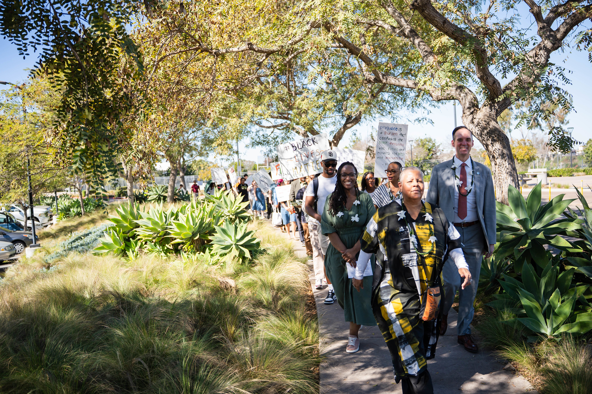 
A group walks under a row of trees to the Rosa Parks Transit Station at Mesa College.
