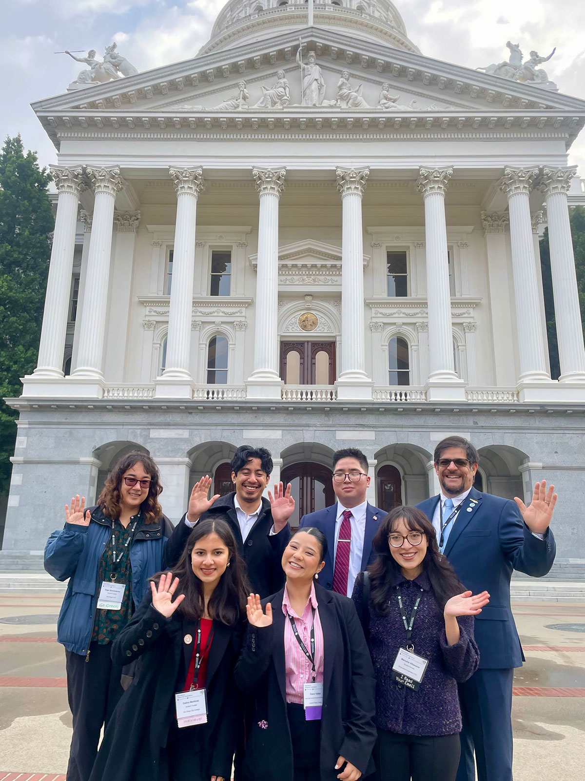 
Seven student leaders wave in front of the Capitol Building in Sacramento
