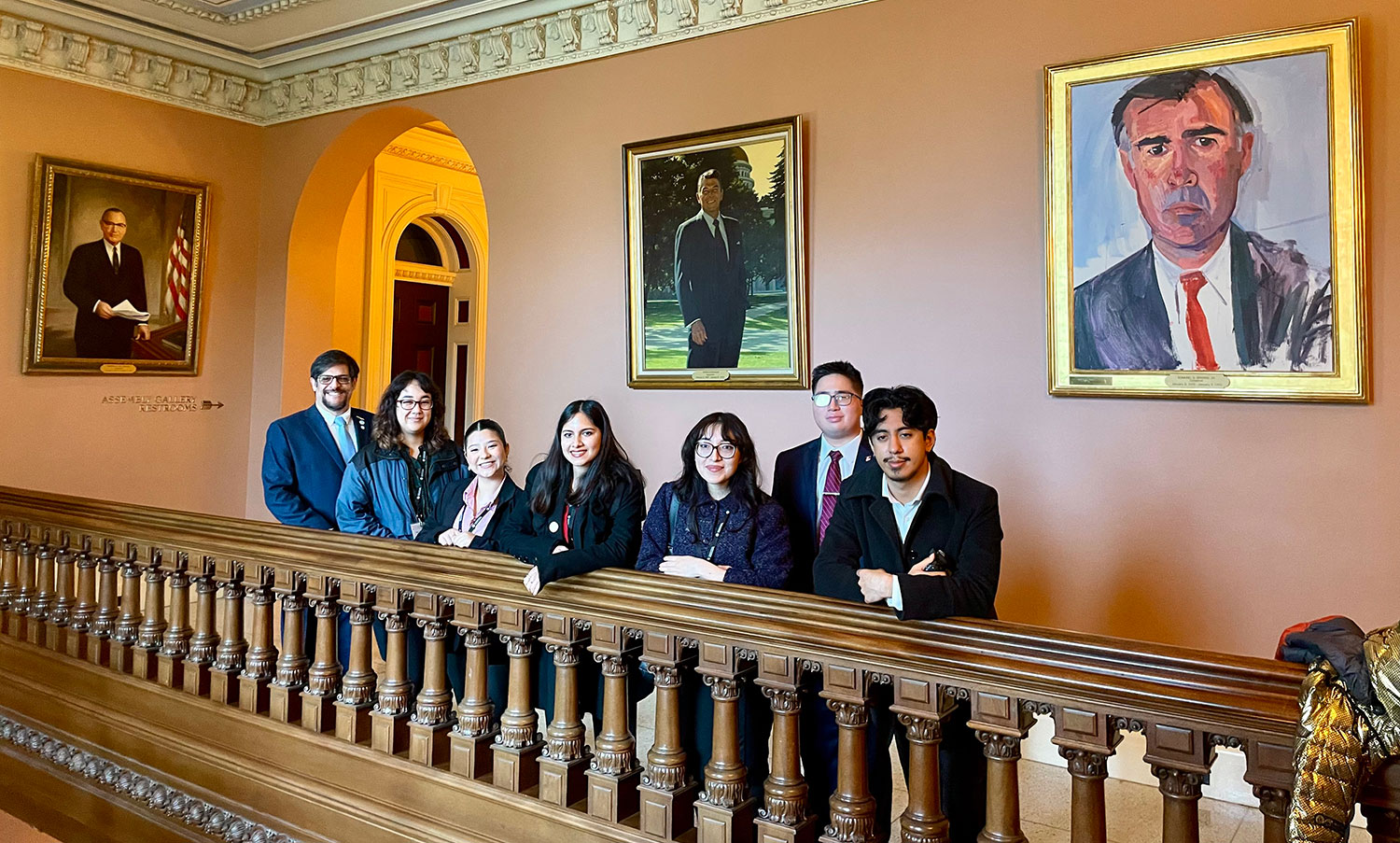 
Seven student leaders in the halls of the Sacramento Capitol Building. There is a portrait of Ronald Regan on the wall behind them.
