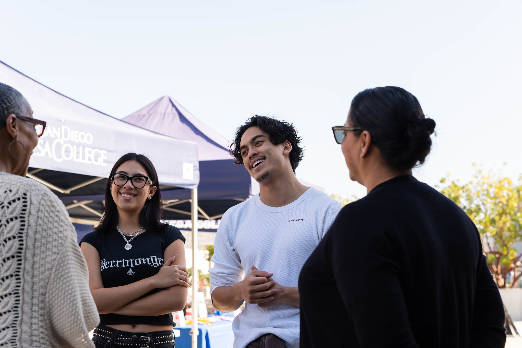 
Four people talking next to Mesa College welcome booths.
