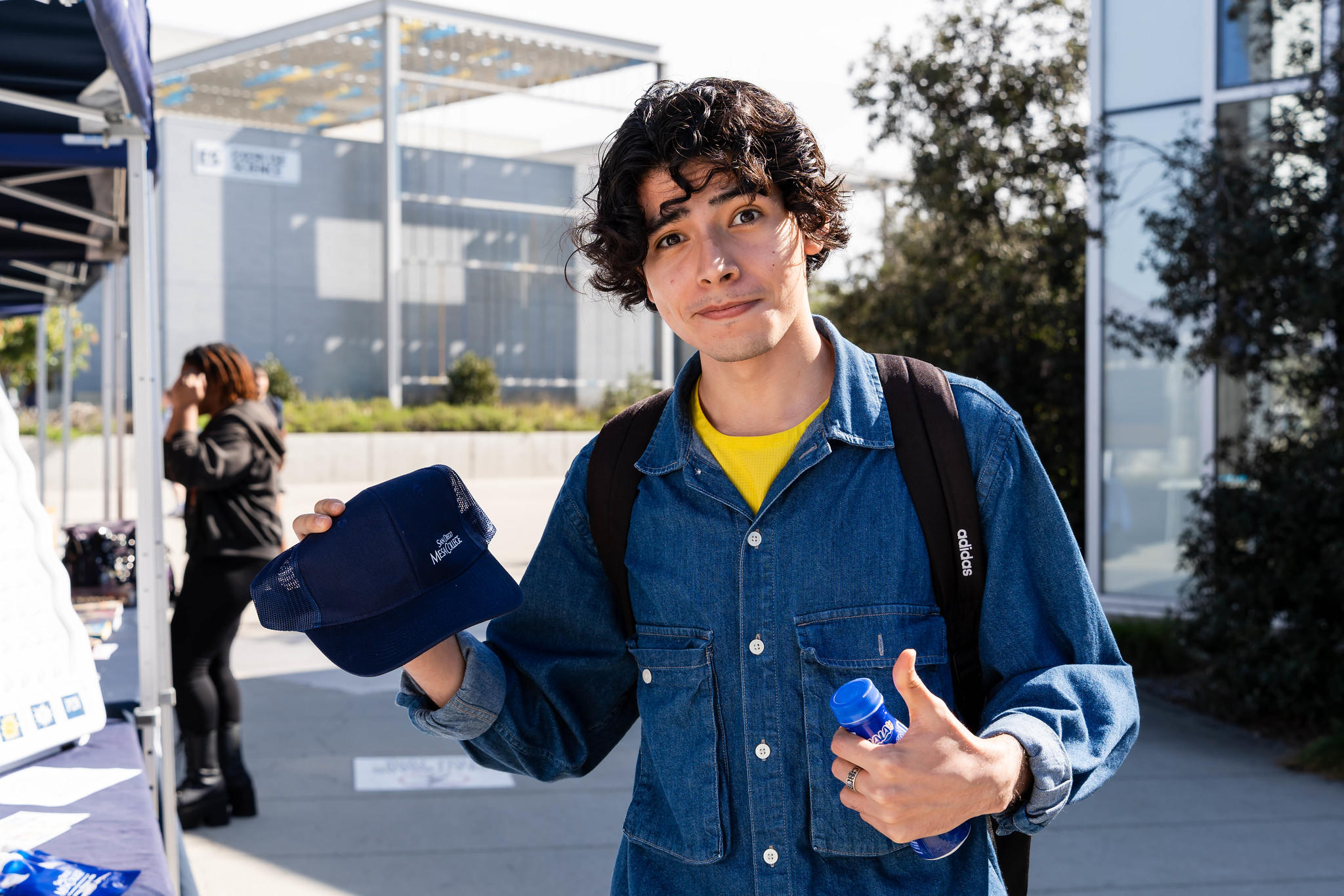 
A student holds up a blue Mesa College hat.
