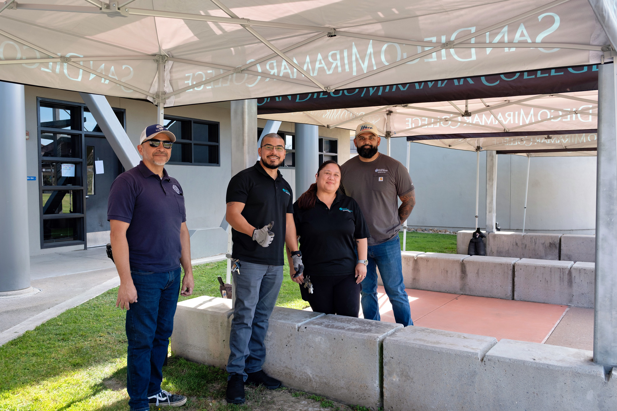 
Four maintence workers under a welcome tent.
