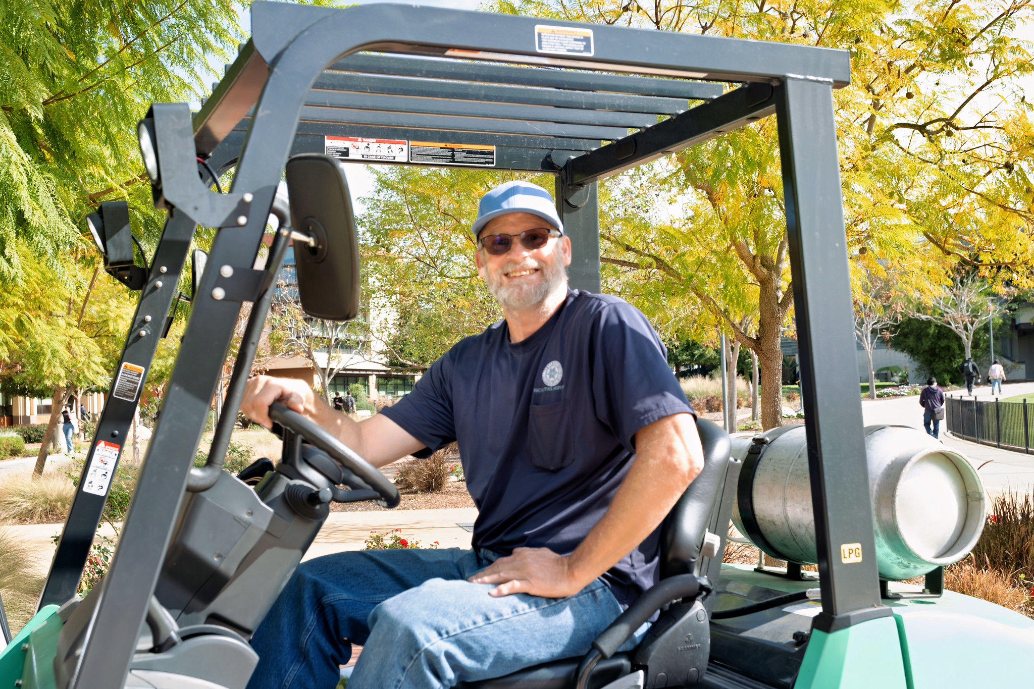 
A maintenence worker drives a golf cart.

