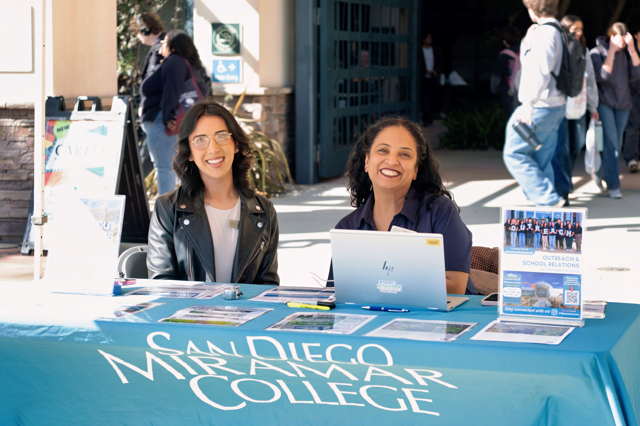 
Two people working at a Miramar College welcome tent.
