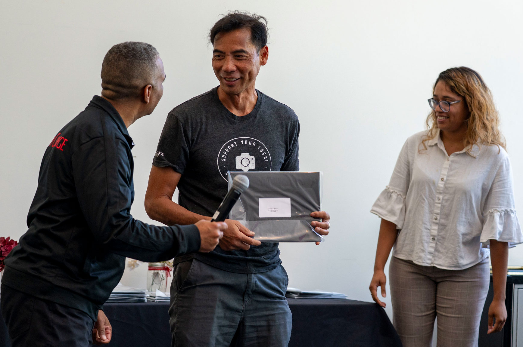 An employee receives a certificate for service. City College President Ricky Shabazz looks on.&nbsp;