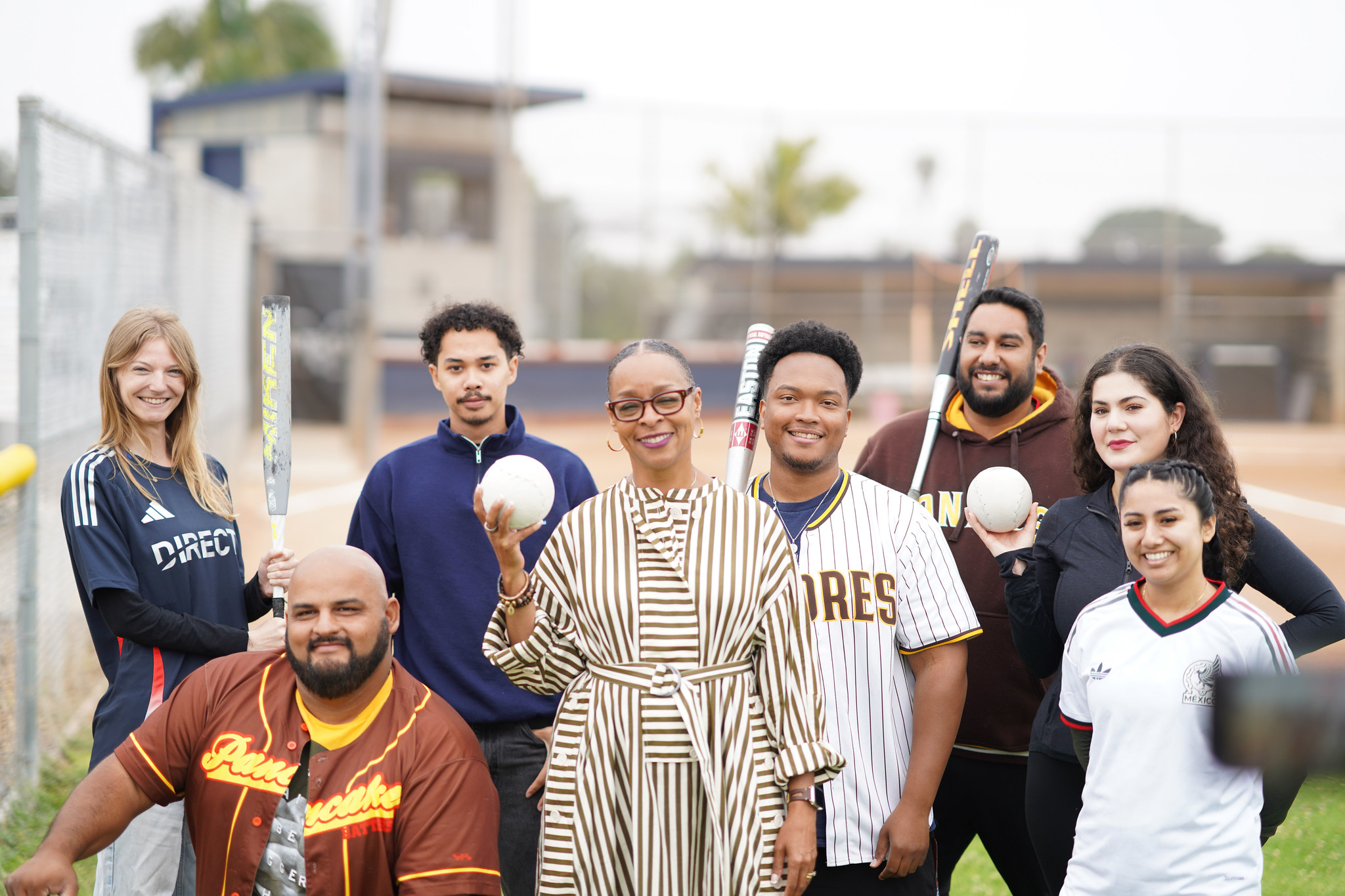 Mesa College President Ashanti Hands with 7 employees. They are holding softballs and bats out on a field.&nbsp;
