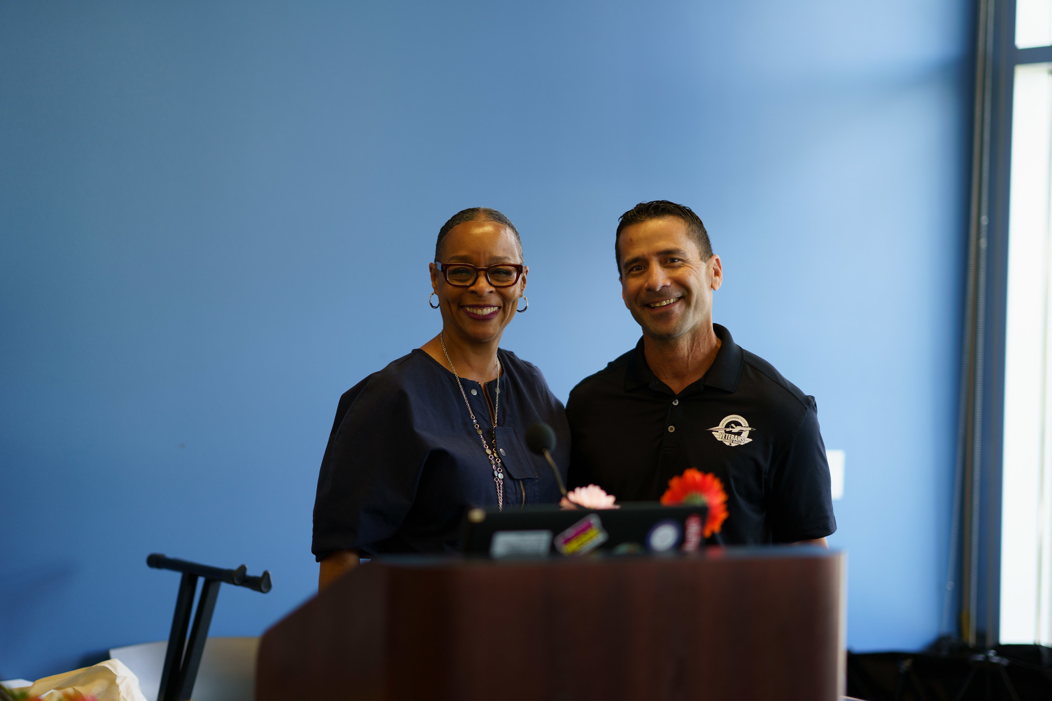 Mesa College President Ashanti Hands with an employee at a podium.