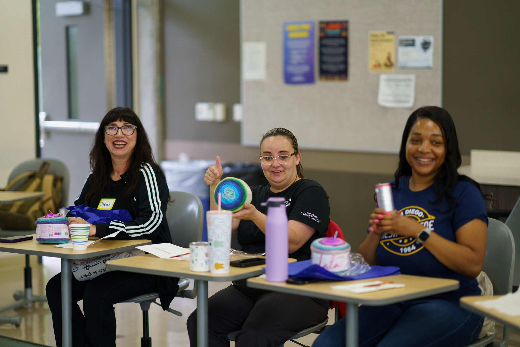 Three employees knitting at a craft table.&nbsp;