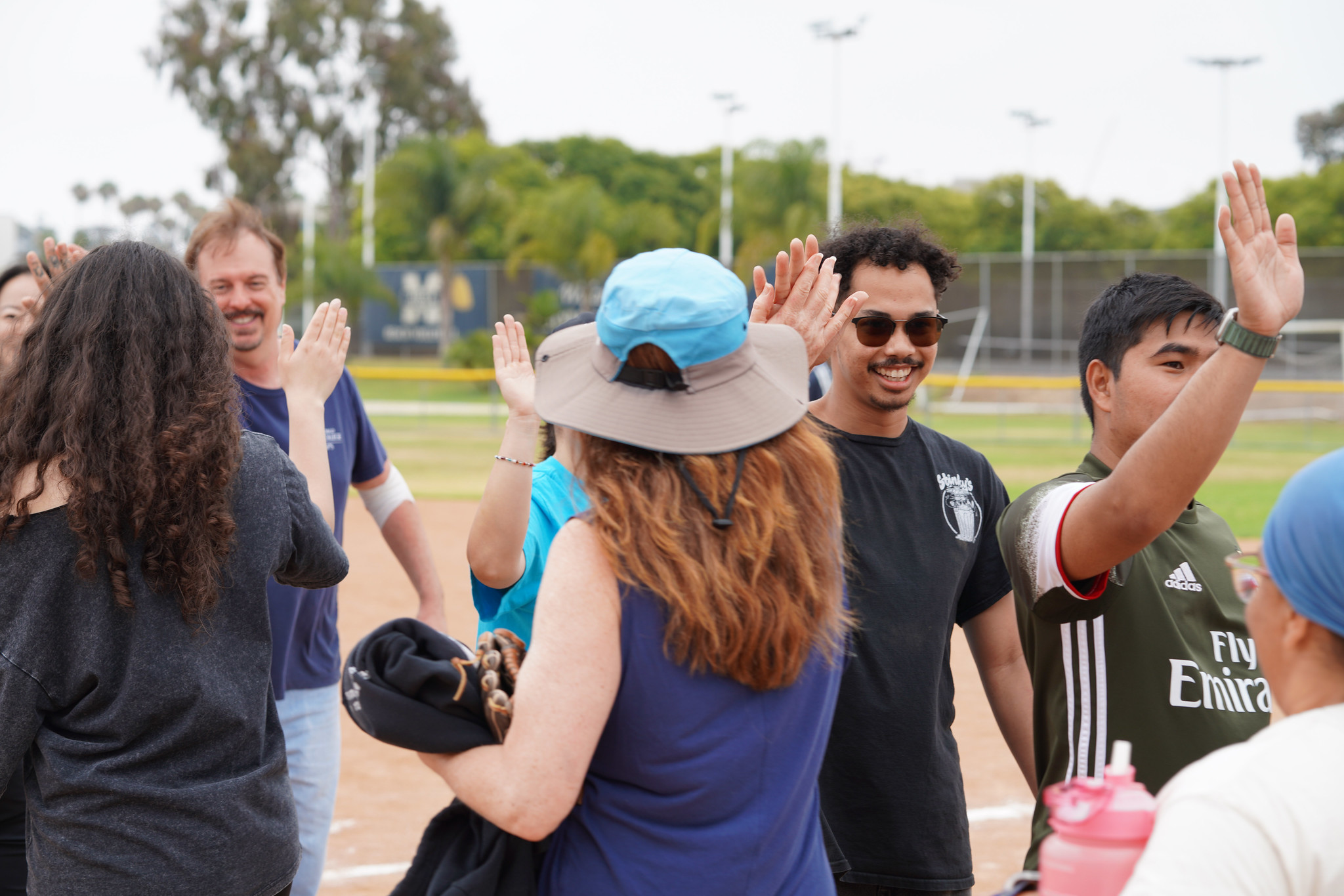 Eight people in two lines give each other high fives as they pass each other.&nbsp;