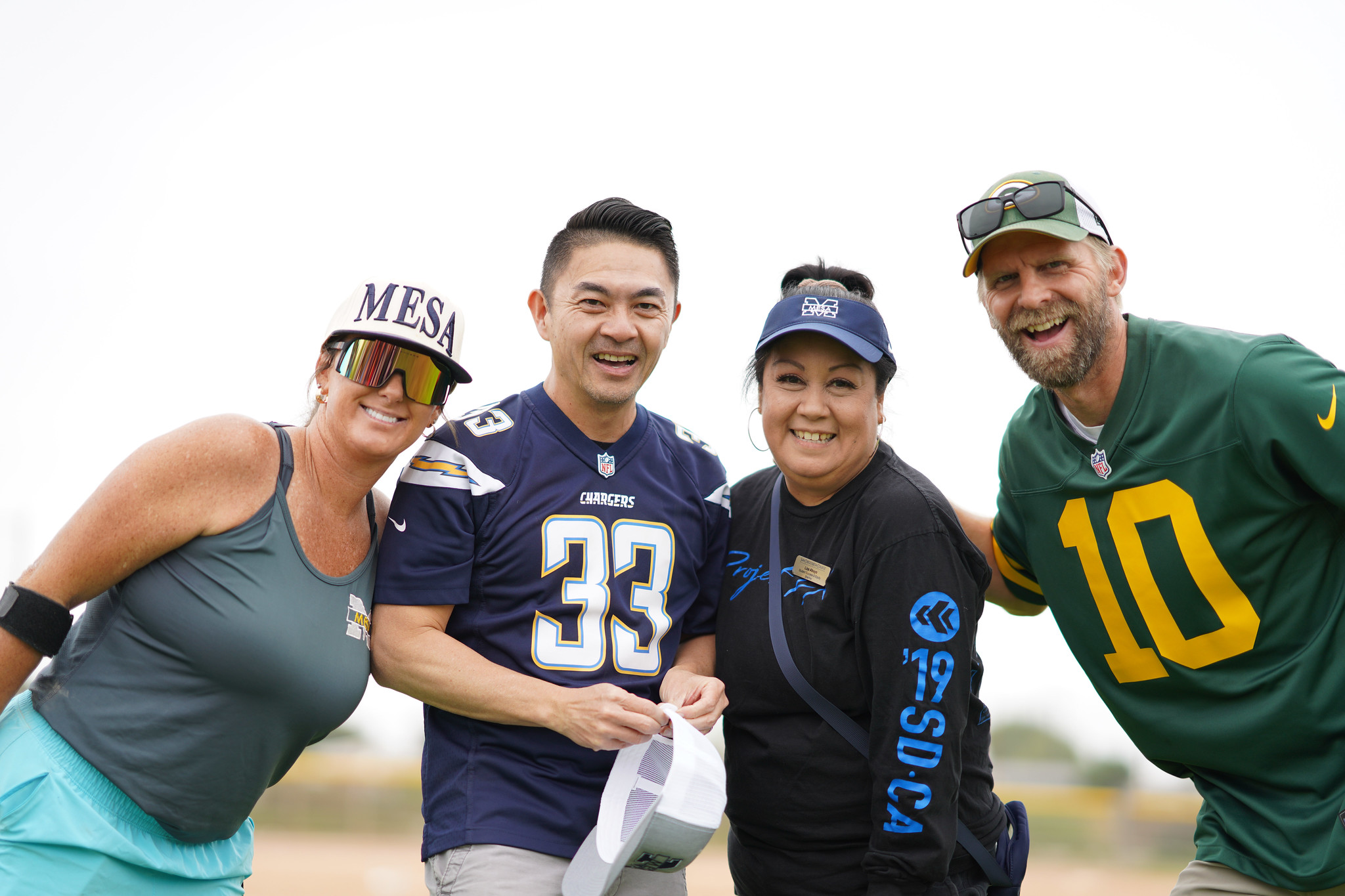 Four Mesa employees in sports attire on the ballfield.&nbsp;