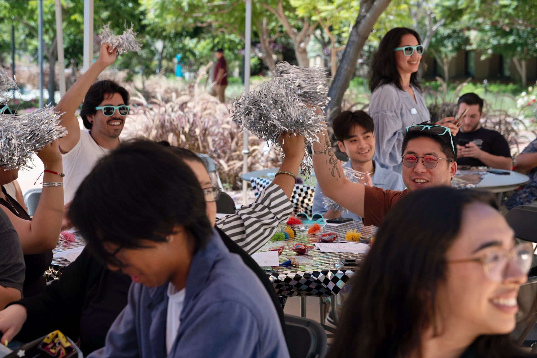 A group seated at a table wave pompoms at the Miramar event.&nbsp;