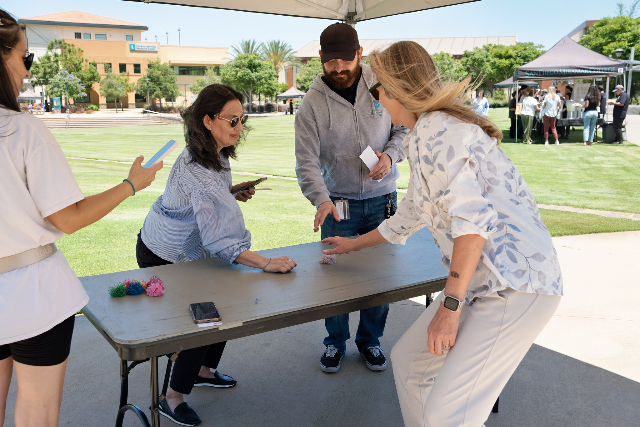 Four Miramar employees gather around a table to play a game.&nbsp;